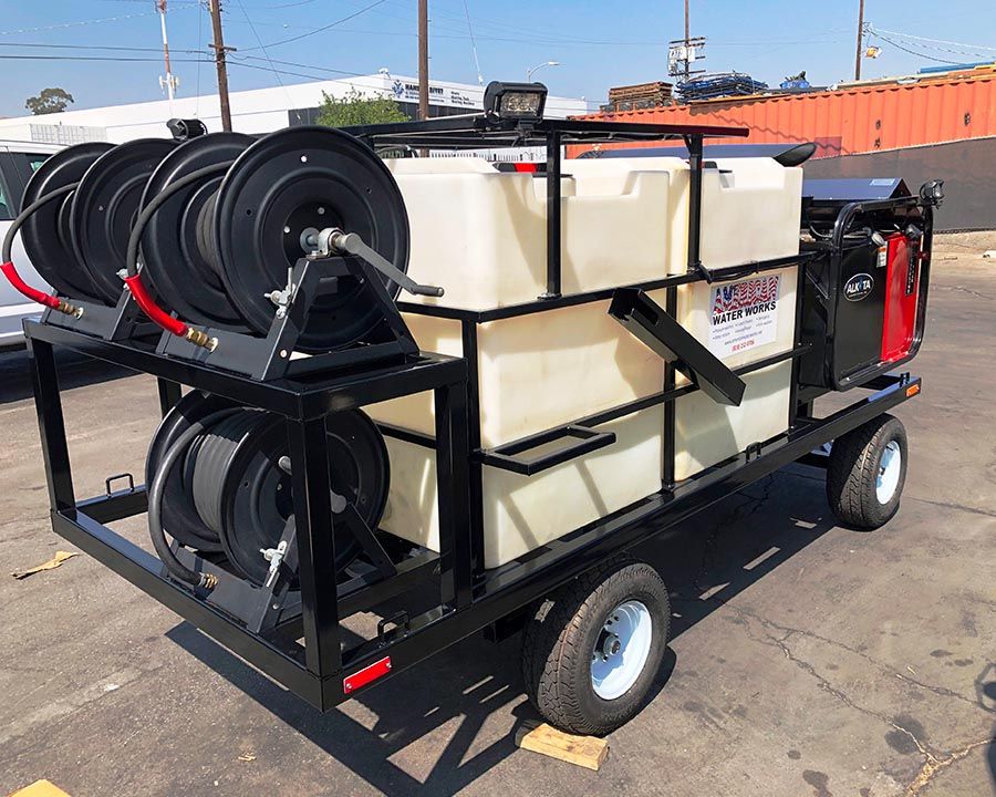 Black-frame trailer rig with four hose reels, a full-length white tank and the American Water Works decal
