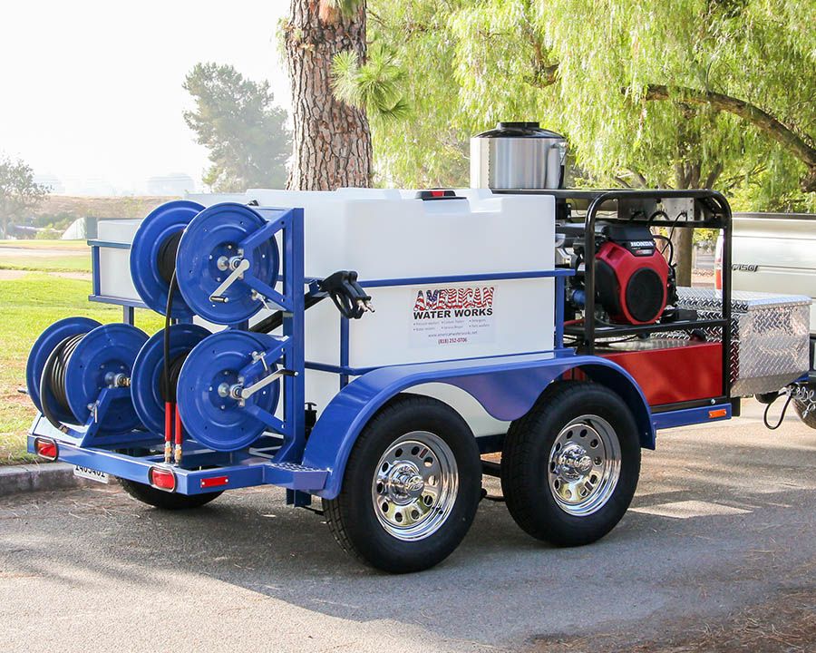 Four blue hose reels on the back of a blue tandem, with a white tank and a hot water machine ahead of them