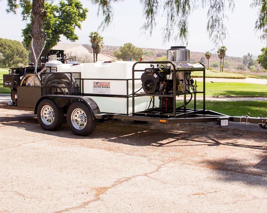 A long black tandem with two tanks, a hot water machine at the front and an Alkota unit with reels at the back