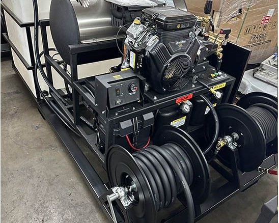 A hot water skid with a tank and hose reels on the shop floor